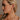 Side view of model's face; model is wearing the Nyomi Raffia & Gold Earrings that have ivory and tan raffia intertwined with gold metal into a circle hanging from tan raffia ball.