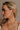 Side view of model's face; model is wearing the Nyomi Raffia & Gold Earrings that have ivory and tan raffia intertwined with gold metal into a circle hanging from tan raffia ball.
