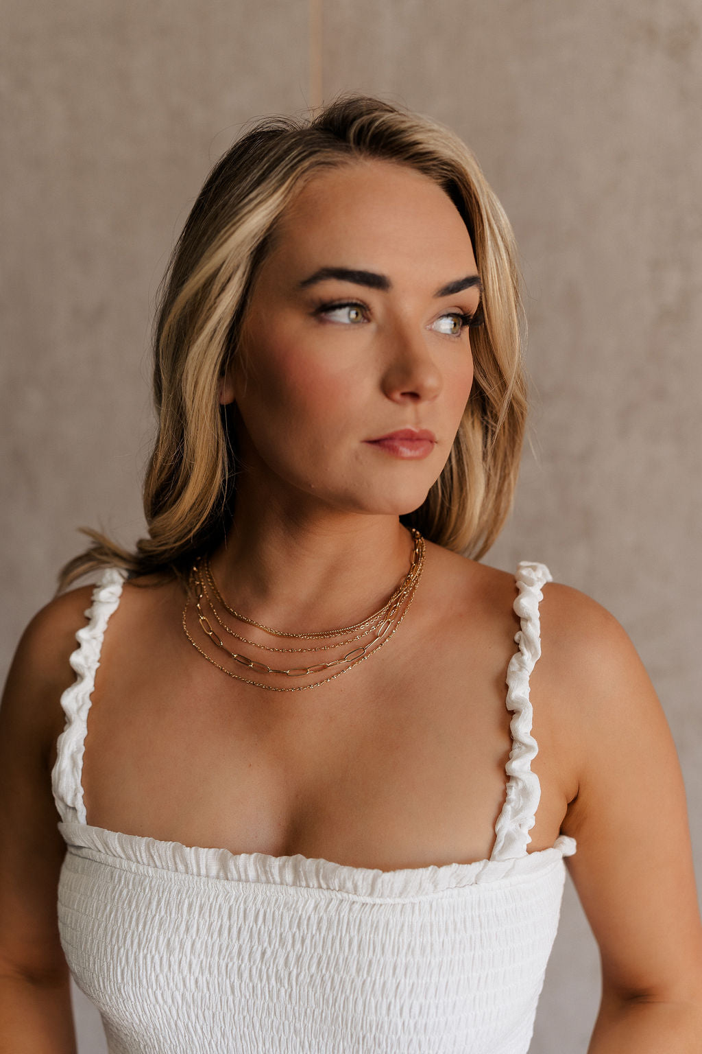 Front view of female model wearing the Madeline Gold Chain Layered Necklace which features four layers of gold chain link linked together with an adjustable clasp closure