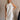 Upper body front view of female model wearing the Mara Sleeveless Mock Neck Tie Back Dress in Off White that has a ruffle mock neck, mini length hem, and tie back.