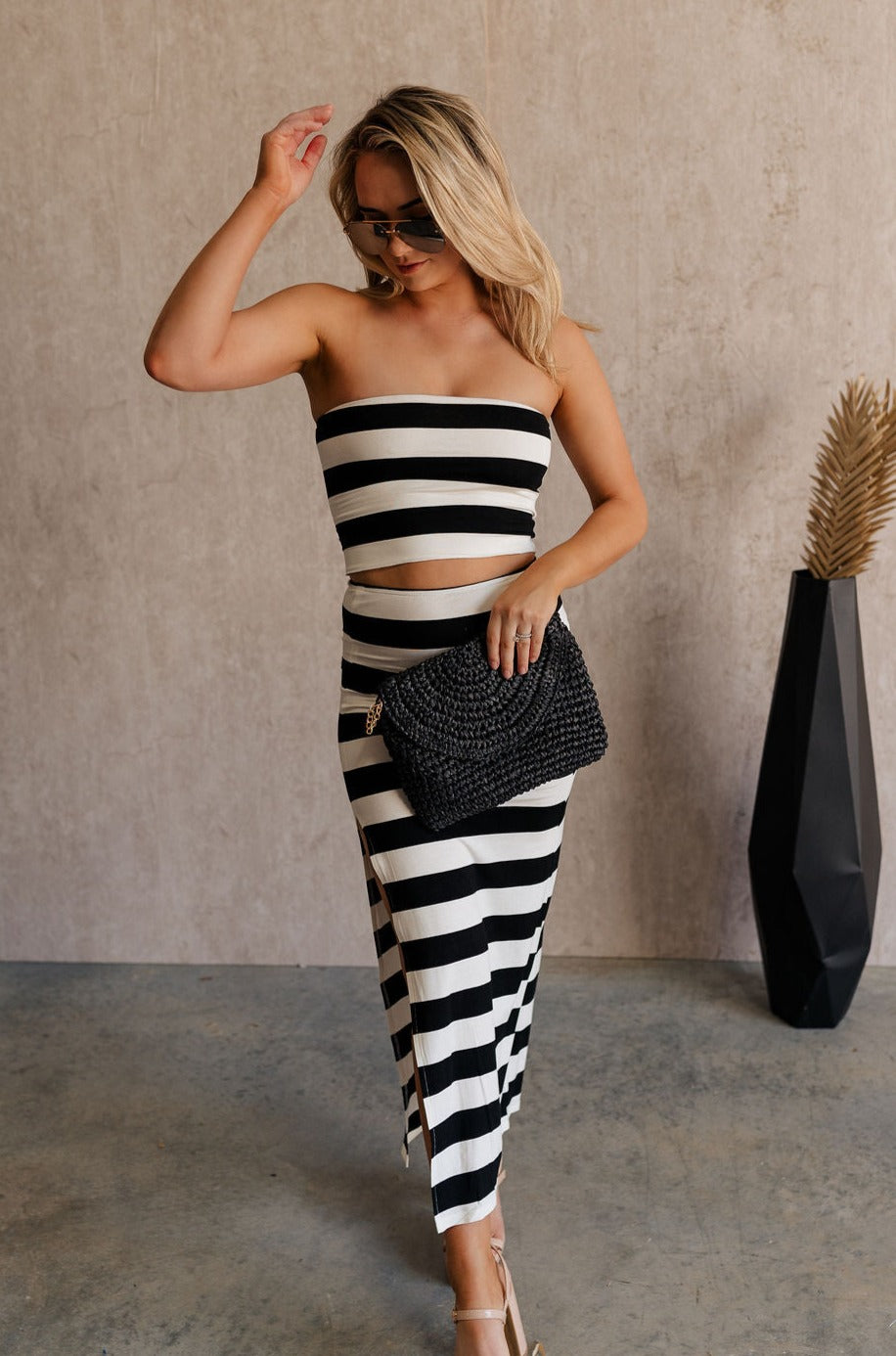 Full body front view of model wearing the Maxine Black & White Striped Midi Skirt that has horizontal black and white stripes and a side slit. Worn with matching top.