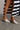 Side view of model wearing the Sunrise Macrame Mule in Natural which feature natural crochet knit fabric, slide on style and 1 inch block heel