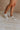 Side view of female model wearing the Alta Sneaker in Off White which features light grey and white suede upper fabric, white sole, and lace up details