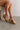 Front side view of female model wearing the Seville Natural Raffia Wedge Sandal which features light natural raffia fabric, cross straps, adjustable buckle closure and cork platform sole
