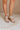Front side view of female model wearing the Sofft Camille Sandal in Tapioca Grey which features light grey upper fabric, Side zipper with matching leather pull, cross straps and stacked block heel