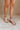 Front side view of female model wearing the Sofft Camille Sandal in Tapioca Grey which features light grey upper fabric, Side zipper with matching leather pull, cross straps and stacked block heel