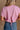 Upper body back view of female model wearing the Belle Pink Short Sleeve Crop Top that has pink fabric, short sleeves, a round neck, and a cropped waist. Worn with jeans.