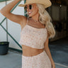 Front upper body view of female model wearing the Mariah Cream Floral Cropped Tank Top that has cream fabric, dusty pink floral print, thin straps, and a cropped waist. Worn with matching skirt.