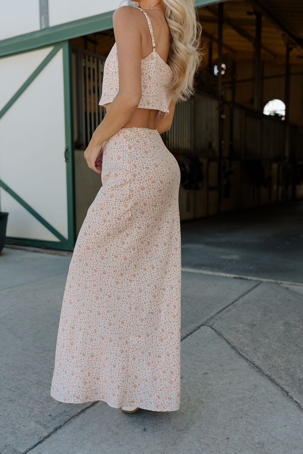 Full body side view of female model wearing the Mariah Cream Floral Midi Skirt that has cream fabric with a dusty rose floral print and elastic waist. Worn with matching tank top