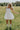 Full body front view of female model wearing the Rosemary White Bubble Hem Mini Dress that has white fabric, a bubble hem, and thin straps.