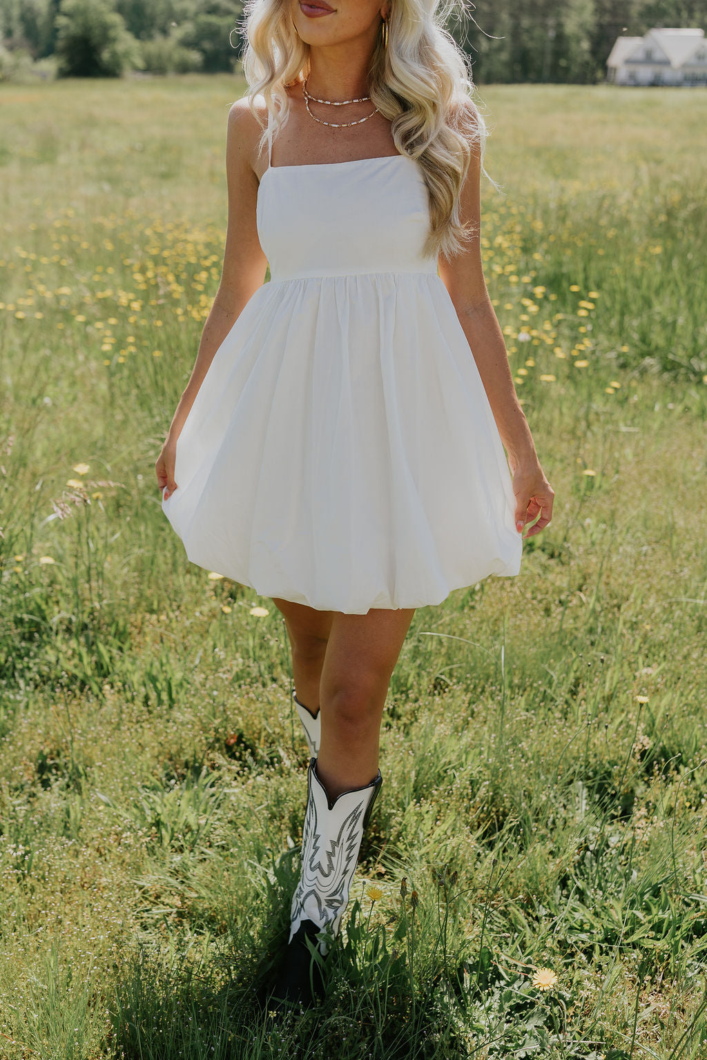 Front view of female model wearing the Rosemary White Bubble Hem Mini Dress that has white fabric, a bubble hem, and thin straps.