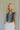 Front view of female model wearing the Brynn Medium Denim Button-Up Vest which features Medium Denim Wash Fabric, Button-Up Front Closure, Cropped Waist, V-Neckline and Sleeveless body.