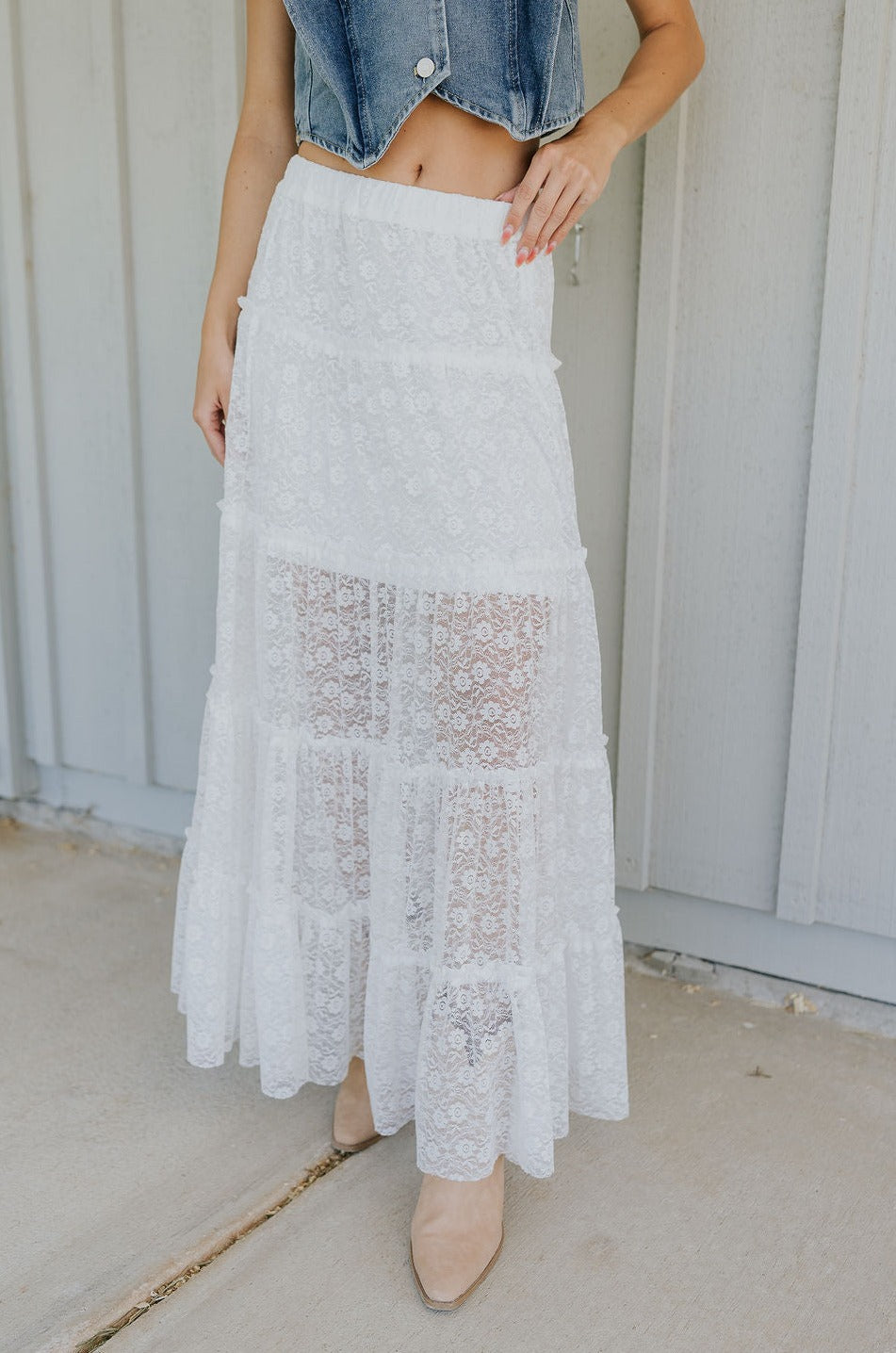 lower body front view of female model wearing the Shiloh White Lace Maxi Skirt that has white lace fabric, half lining, and an elastic waist. 