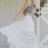 Full body side view of female model wearing the Shiloh White Lace Maxi Skirt that has white lace fabric, half lining, and an elastic waist. model shown twirling.