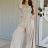 Full body view of female model wearing the Carissa Washed Taupe Tiered Flare Pants which features Washed Taupe Cotton Fabric, Side Tiered Design, Flare Pants, Elastic Waistband with Drawstring Tie and Side Pockets