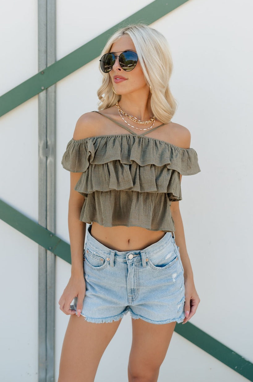 Front view of female model wearing the Kamila Olive Ruffle Off-The-Shoulder Top which features Olive Green Cotton Fabric, Ruffle Tiered Body, Adjustable Straps and Cropped Waist