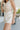Side view of female model wearing the Ivy White Drawstring Tie Shorts which features White Lightweight Fabric, Pockets On Each Side, Elastic Waistband and Drawstring Tie