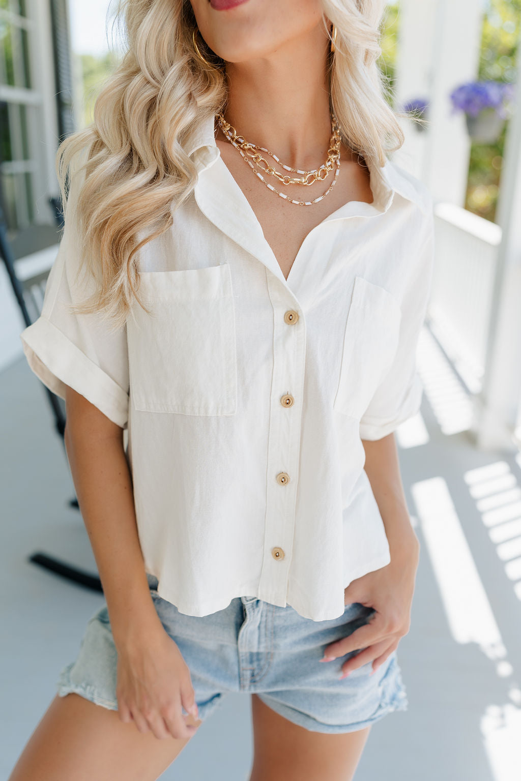 Close up view of female model wearing the Cora White Short Sleeve Button-Up Top which features Off White Linen Fabric, Wooden Button Up Front Closure, Collared Neckline, Short Sleeves and Front Chest