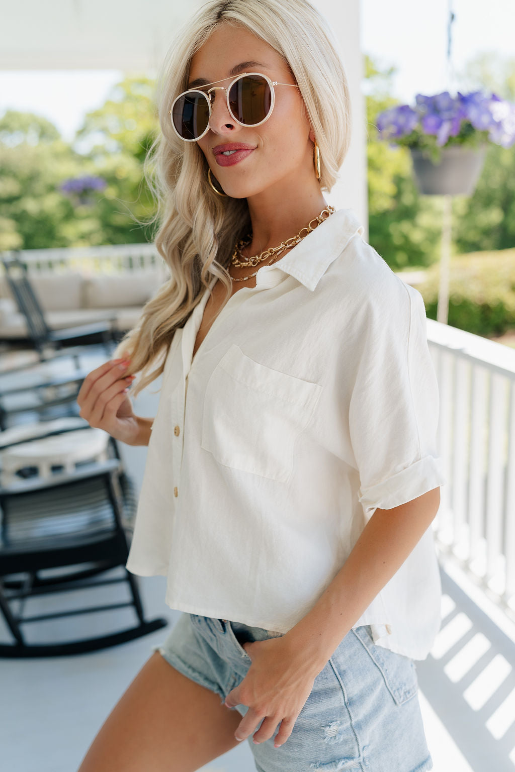 Side view of female model wearing the Cora White Short Sleeve Button-Up Top which features Off White Linen Fabric, Wooden Button Up Front Closure, Collared Neckline, Short Sleeves and Front Chest