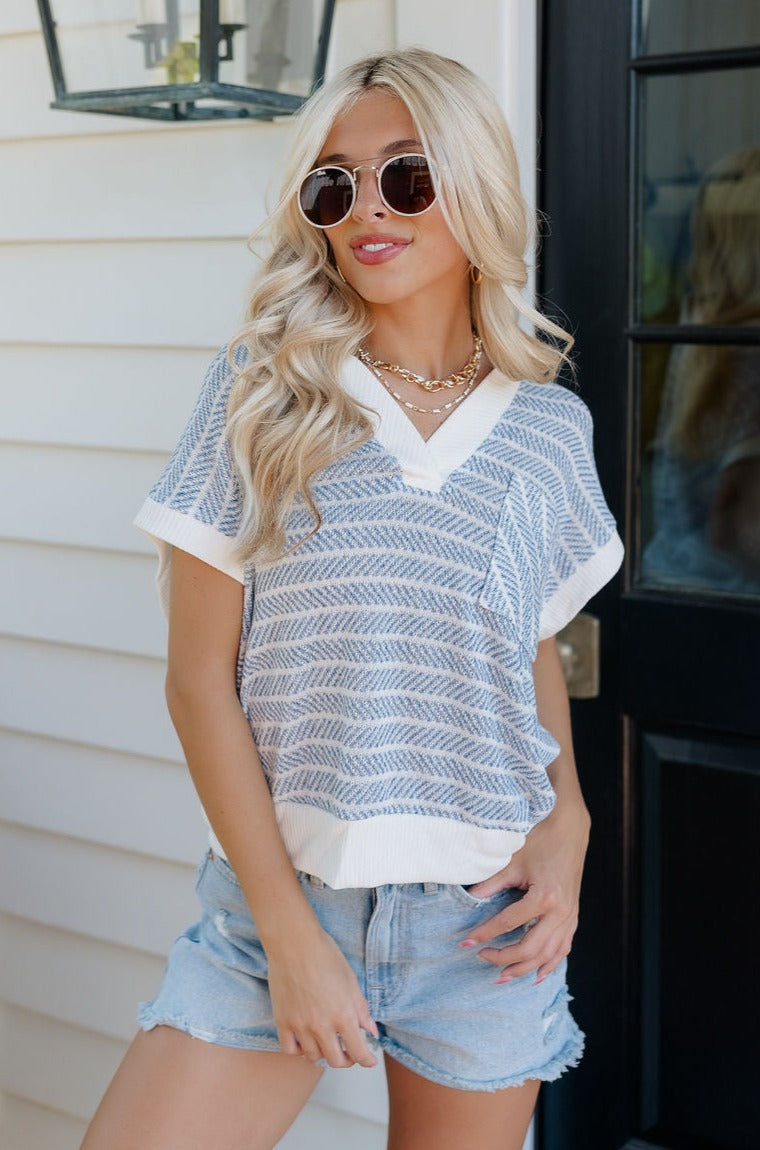 Front view of female model wearing the Alexa Blue & White Stripe Short Sleeve Top which features White and Blue Stripe Pattern, White Thick Hem Details, Short Sleeves, Left Front Chest Pocket and V-Neckline with Collar