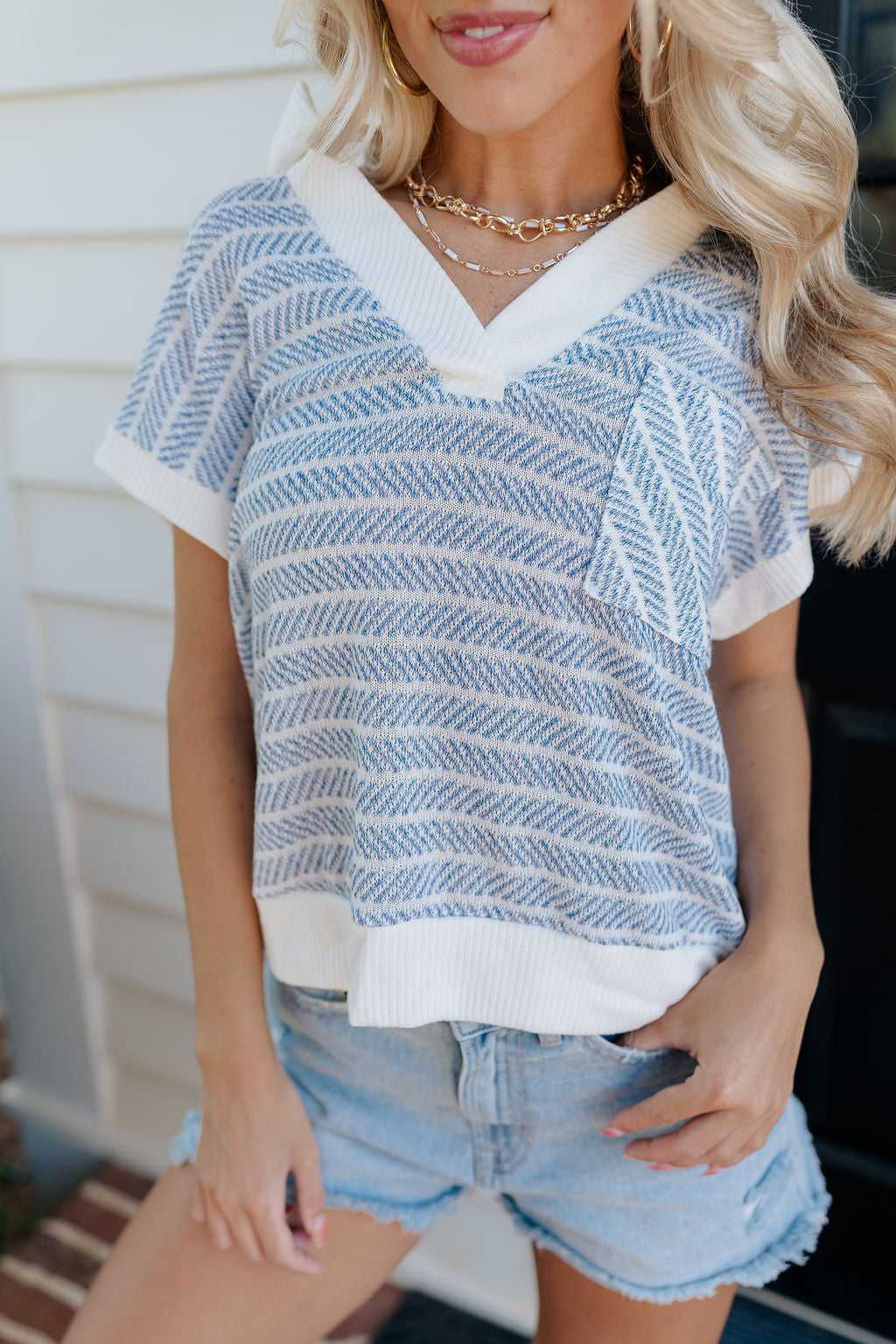 Close up view of female model wearing the Alexa Blue & White Stripe Short Sleeve Top which features White and Blue Stripe Pattern, White Thick Hem Details, Short Sleeves, Left Front Chest Pocket and V-Neckline with Collar