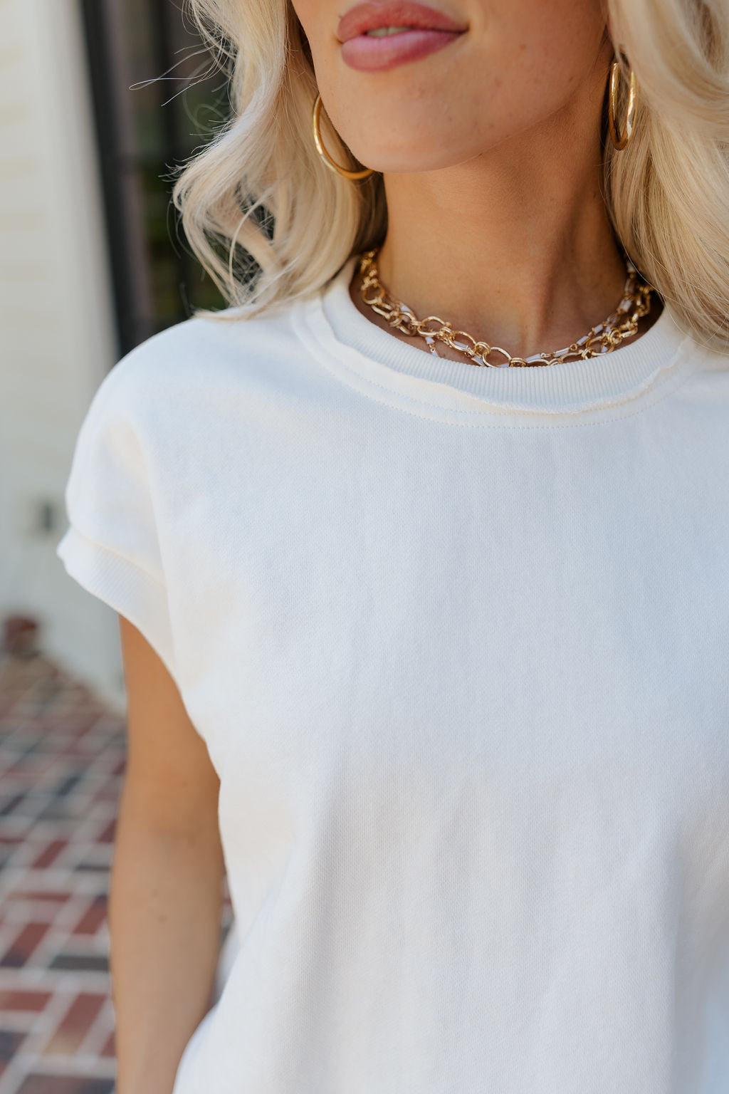 Close up view of female model wearing the Ivy Cream Sleeveless Top which features White Cotton Fabric, Raw Thread Hem Details, Sleeveless andRound Neckline.