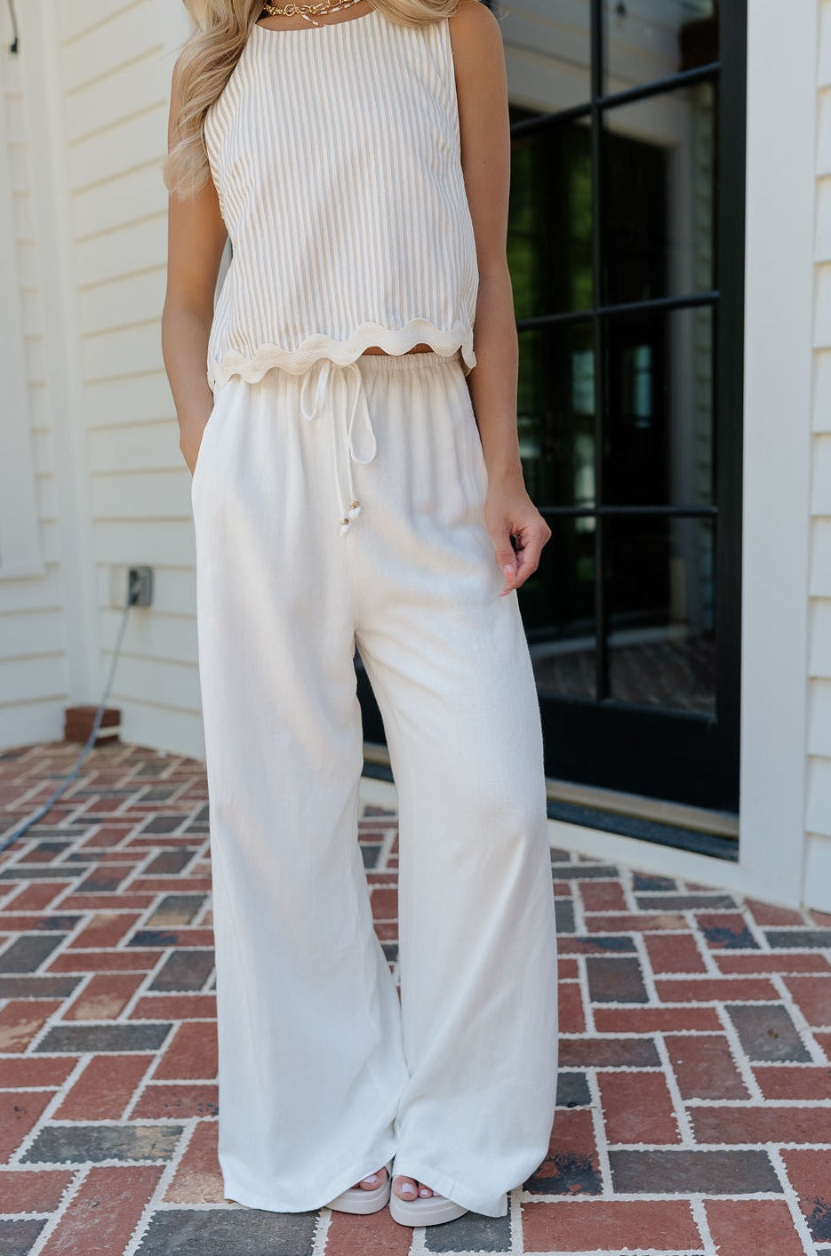 Front view of female model wearing the Alice Off White Wide Leg Drawstring Pants which features Off White Lightweight Linen Fabric, Off White Lining, Wide Pant Legs, Side Pockets and Elastic Waistband with Drawstring Tie