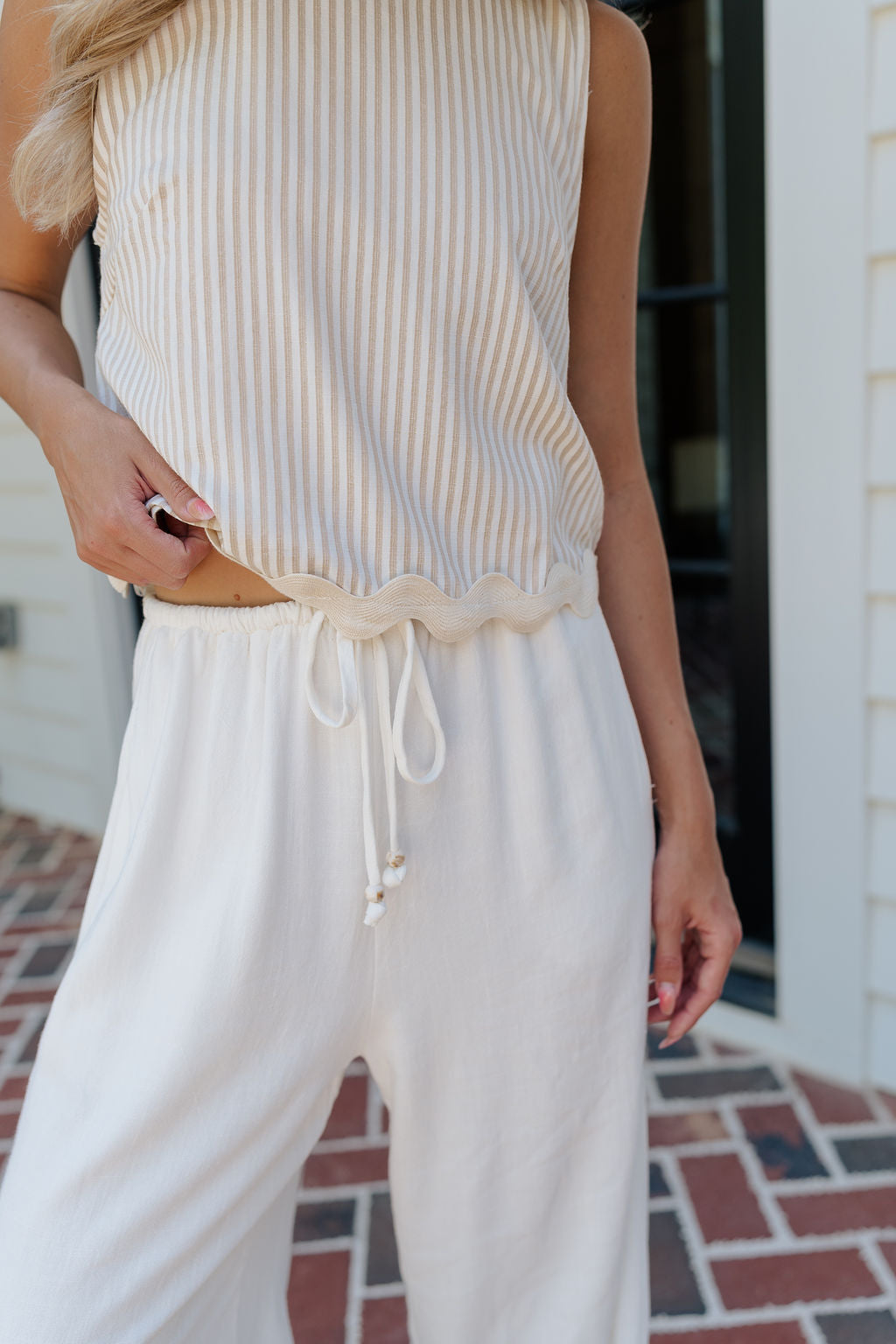 Close up view of female model wearing the Alice Off White Wide Leg Drawstring Pants which features Off White Lightweight Linen Fabric, Off White Lining, Wide Pant Legs, Side Pockets and Elastic Waistband with Drawstring Tie