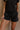 Close up front view of female model wearing the Kennedy Washed Black Drawstring Shorts which features Washed Black Cotton Fabric, Side Pockets and Elastic Waistband with Drawstring Tie
