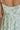 Close up back view of female model wearing the Kira Mint Green Floral Midi Dress which features Mint green fabric, Green floral print, Floral eyelet embroidery, V-neckline, Adjustable straps and Green lining