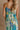 Back view of female model wearing the Mallory Green Multi Floral Sleeveless Midi Dress which features Green, blue, white, and yellow floral print, Round neckline, Adjustable straps, Keyhole back with tie closure and White lining