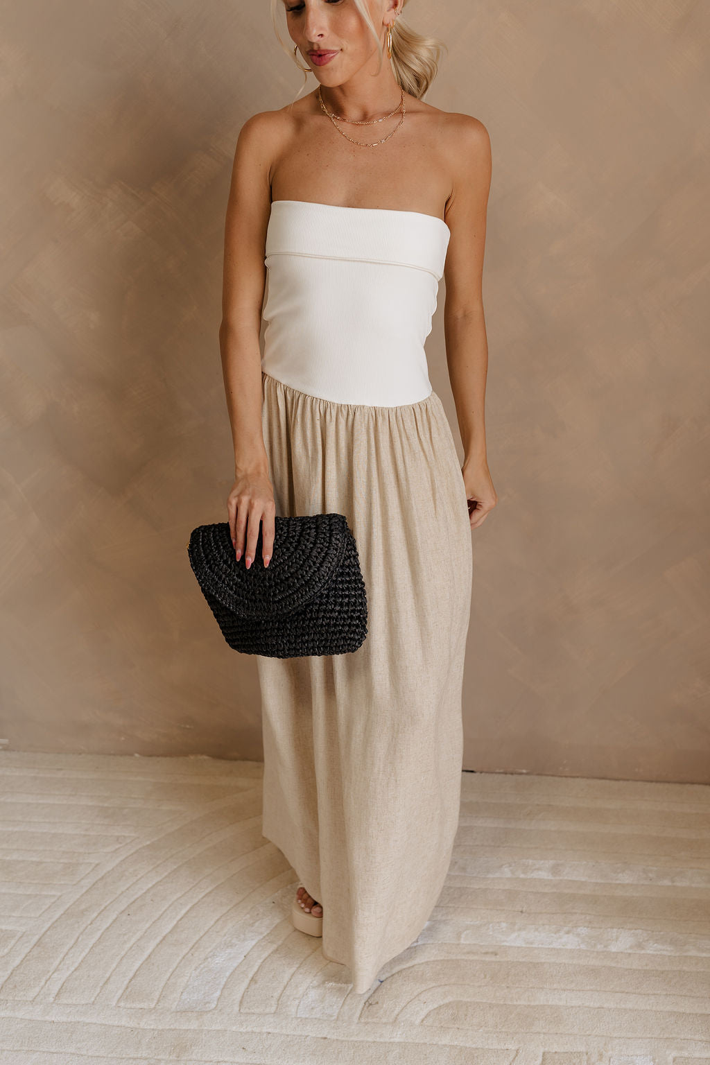 Front view of female model wearing the Ellie White & Oatmeal Strapless Maxi Dress which features White Ribbed Upper, Oatmeal Linen Fabric, Maxi Length, Back Slit Detail and Strapless