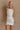 Front view of female model wearing the Isla White Silver Ruched Halter Neckline Mini Dress which features White Silver Fabric, White Lining, Ruched Details, Overlap Hem, Halter Neckline and Monochrome Back Zipper with Hook Closure
