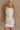 Front view of female model wearing the Isla White Silver Ruched Halter Neckline Mini Dress which features White Silver Fabric, White Lining, Ruched Details, Overlap Hem, Halter Neckline and Monochrome Back Zipper with Hook Closure