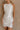 Front view of female model wearing the Isla White Silver Ruched Halter Neckline Mini Dress which features White Silver Fabric, White Lining, Ruched Details, Overlap Hem, Halter Neckline and Monochrome Back Zipper with Hook Closure