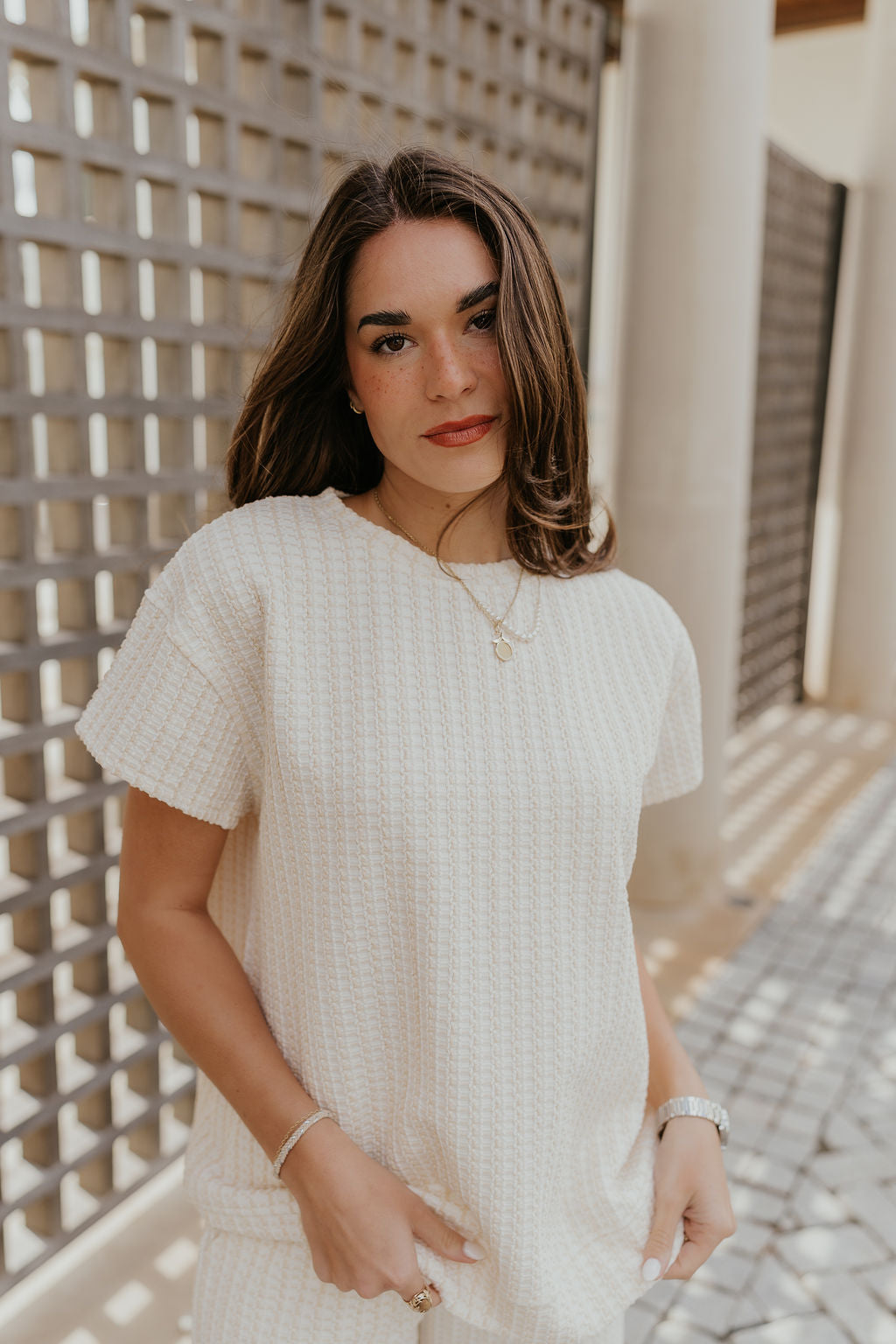 Front view of female model wearing the Willow Cream Woven Short Sleeve Top which features Cream and White Woven Design, Thick Hem, Round Neckline and Short Sleeves