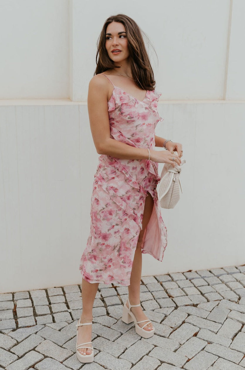 Full body view of female model wearing the Maya Pink Multi Floral Ruffle Slit Midi Dress which features Pink Multi Floral Sheer Fabric, Light Pink Lining, Ruffle Tier Details, Side Slit Detail, Sweetheart Neckline, Adjustable Straps and Side Zipper with Hook Closure
