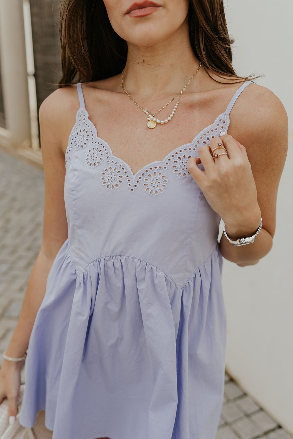 Close up view of female model wearing the Lucia Lavender Eyelet Sleeveless Mini Dress which features Lavender Lightweight Fabric, Lavender Lining, Mini Length, Eyelet Pattern, Scalloped Upper Hem and Adjustable Straps