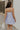 Back view of female model wearing the Lucia Lavender Eyelet Sleeveless Mini Dress which features Lavender Lightweight Fabric, Lavender Lining, Mini Length, Eyelet Pattern, Scalloped Upper Hem and Adjustable Straps