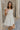 Frontal side view of female model wearing the Blakely Ecru Crochet Babydoll Mini Dress which features Ecru Lightweight Fabric, Ecru Crochet Knit Upper, Ecru Lining, Mini Length, Tie Straps and Scoop Neckline