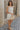 Full body side view of female model wearing the Blakely Ecru Crochet Babydoll Mini Dress which features Ecru Lightweight Fabric, Ecru Crochet Knit Upper, Ecru Lining, Mini Length, Tie Straps and Scoop Neckline