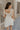 back view of female model wearing the Blakely Ecru Crochet Babydoll Mini Dress which features Ecru Lightweight Fabric, Ecru Crochet Knit Upper, Ecru Lining, Mini Length, Tie Straps and Scoop Neckline