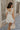 Back view of female model wearing the Blakely Ecru Crochet Babydoll Mini Dress which features Ecru Lightweight Fabric, Ecru Crochet Knit Upper, Ecru Lining, Mini Length, Tie Straps and Scoop Neckline