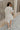 Full body back view of female model wearing the Juliette Linen Fray Mini Dress which features Linen Lightweight Fabric, Fray Hem Details, V-Neckline with a Collar and Folded Short Sleeves