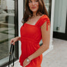 Side view of female model wearing the Rosalie Red Sleeveless Romper which features Tomato Red Lightweight Fabric, Ruffle Hem, Elastic Waistband, Square Neckline and Thick Straps with Tie Details