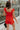 Back view of female model wearing the Rosalie Red Sleeveless Romper which features Tomato Red Lightweight Fabric, Ruffle Hem, Elastic Waistband, Square Neckline and Thick Straps with Tie Details
