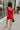 Full body back view of female model wearing the Rosalie Red Sleeveless Romper which features Tomato Red Lightweight Fabric, Ruffle Hem, Elastic Waistband, Square Neckline and Thick Straps with Tie Details