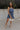 ull body view of female model wearing the Lena Navy & White Polka Dot Strapless Mini Dress which features Navy and Cream Polka Dot Design, Ruffle Hem Skirt, Upper Ruffle Detail and Strapless