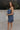 Full body side view of female model wearing the Lena Navy & White Polka Dot Strapless Mini Dress which features Navy and Cream Polka Dot Design, Ruffle Hem Skirt, Upper Ruffle Detail and Strapless
