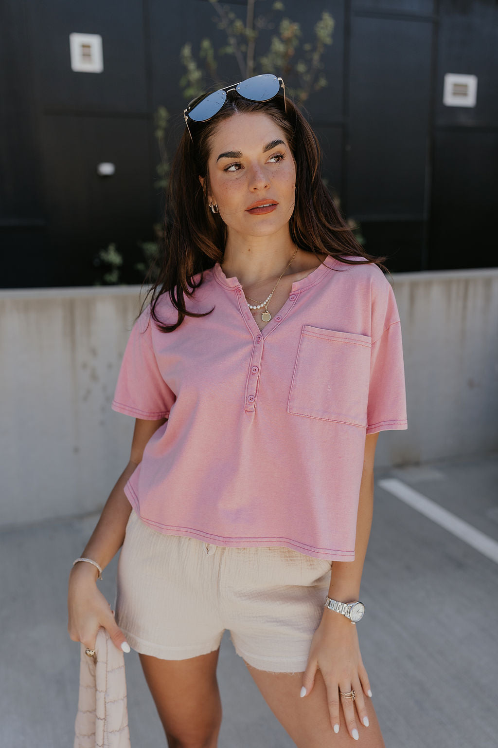 Front view of model wearing the Elise Pink Cropped Short Sleeve Tee that has pink knit fabric, a button up neckline, a chest pocket, and short sleeves.